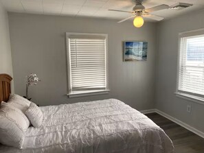 A bedroom with a bed, two windows with blinds, a ceiling fan, and a wall-mounted light fixture. - Less than 2 blocks from Beach w/ 4 beach tags (Seaside Heights)
