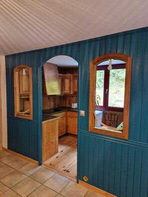 Une cuisine avec des meubles de rangement en bois, un évier et une fenêtre donnant sur un paysage verdoyant.