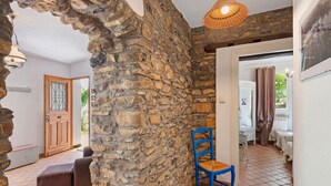 A room with a stone wall, a wooden door, a blue chair, and a hanging light fixture.