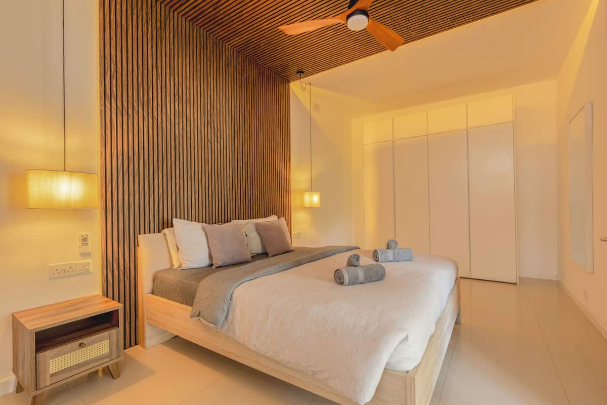 Un dormitorio con cama, mesitas de noche, ventilador de techo y armario.