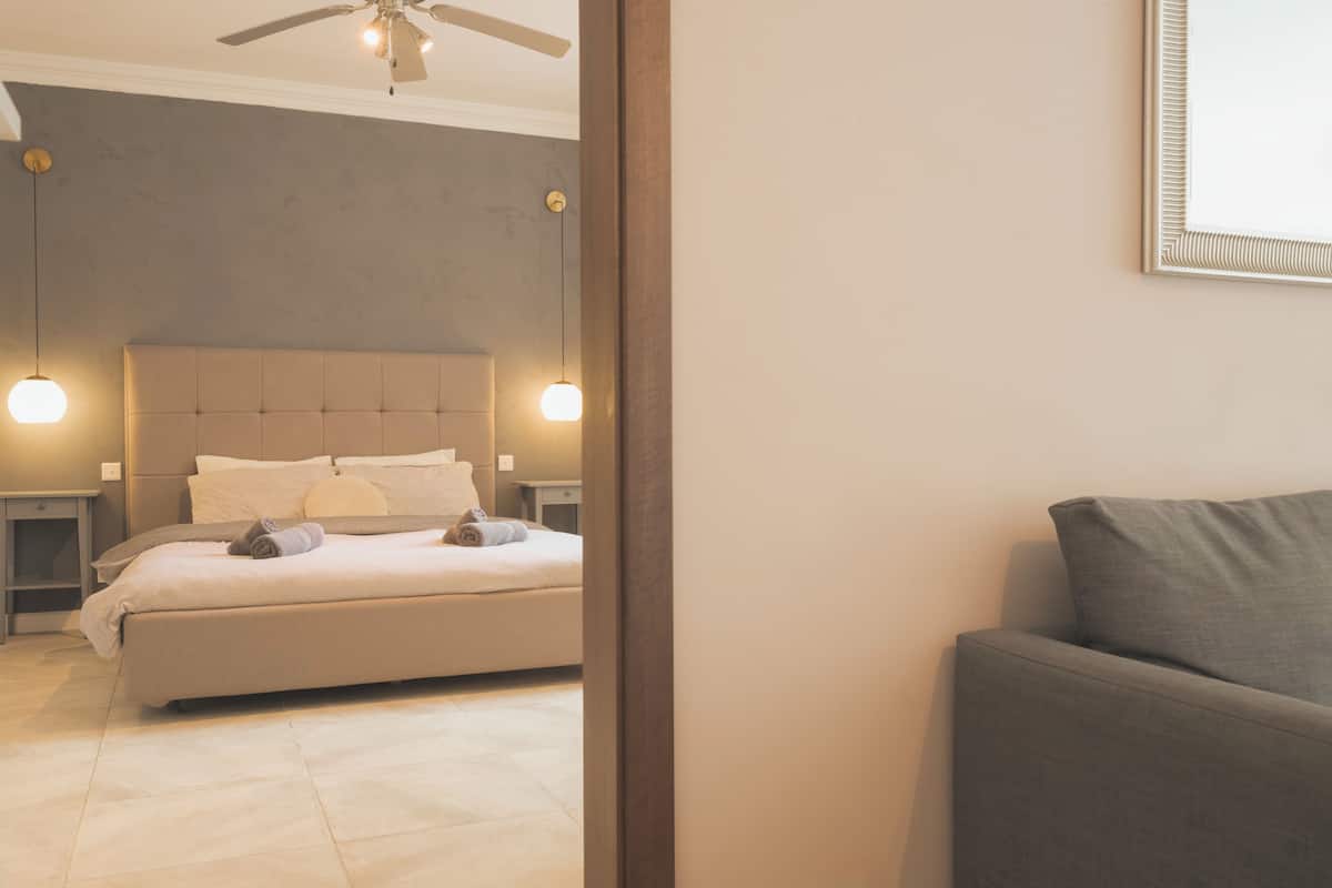 Un dormitorio con cama, mesitas de noche, ventilador de techo e iluminación colgante.