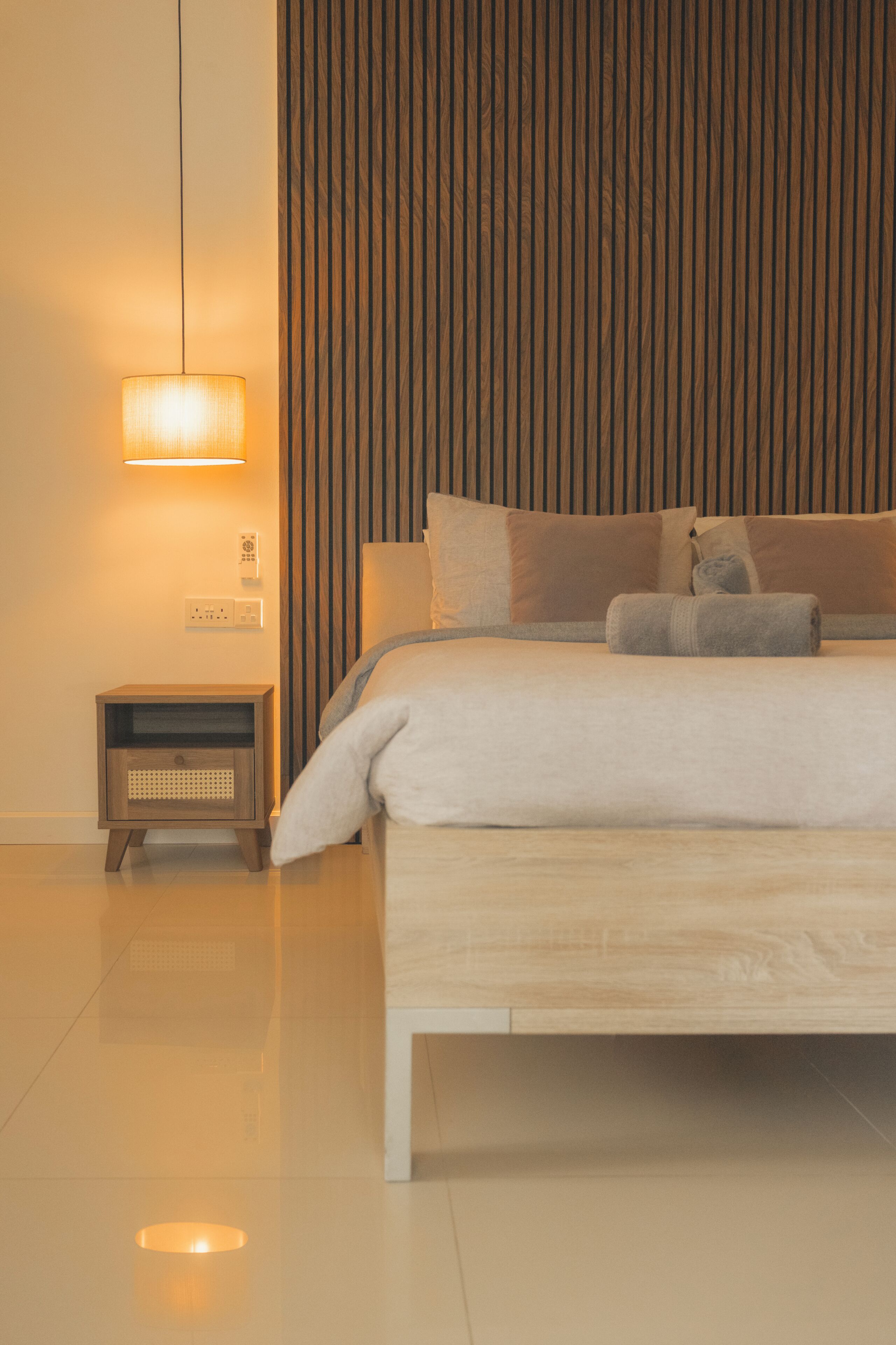 Ein modernes Schlafzimmer mit einem großen Bett, einem Nachttisch und einer wandmontierten Lampe.
