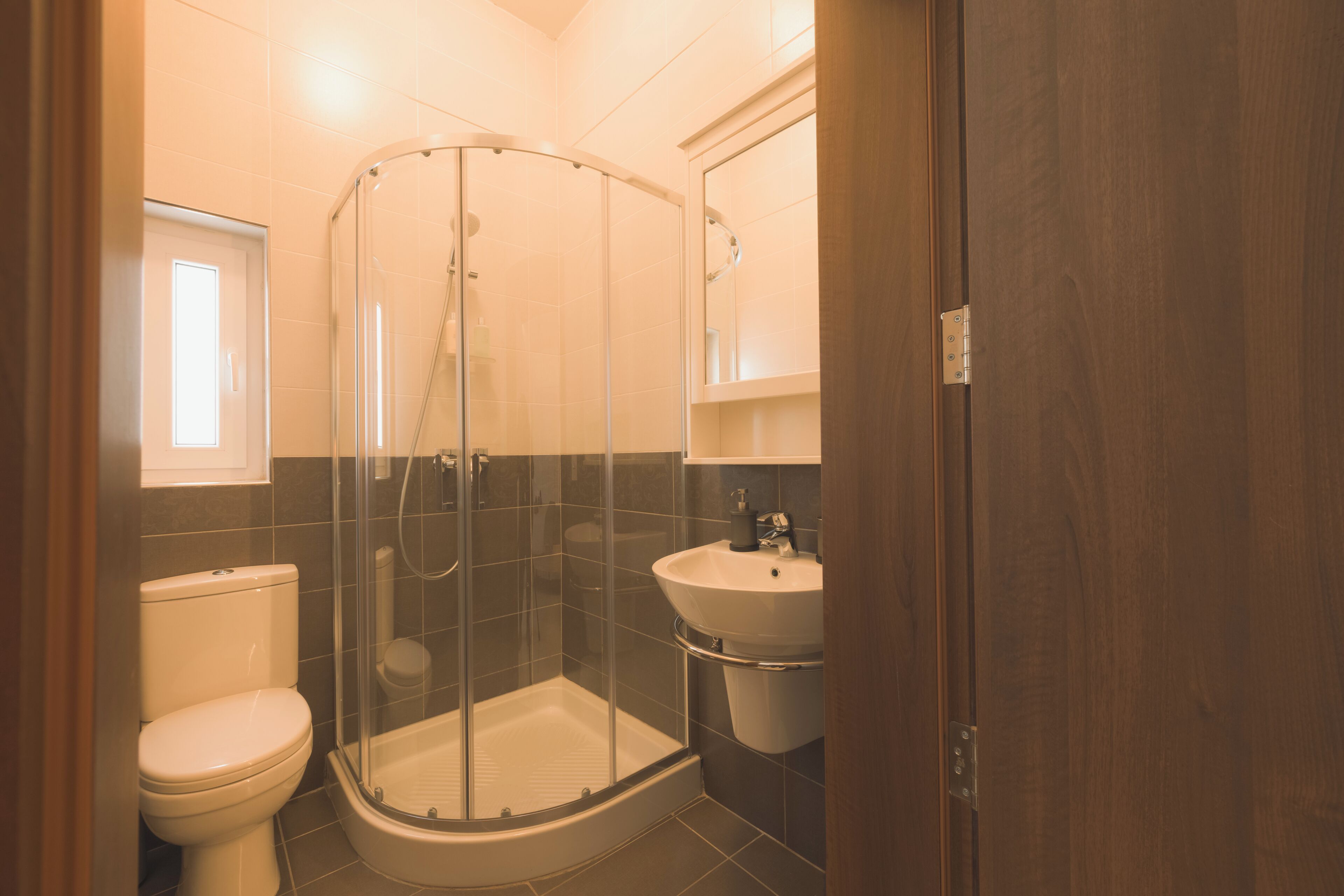 A bathroom with a glass-enclosed shower, a toilet, and a sink.