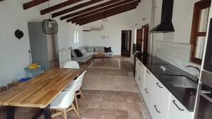 A kitchen with a wooden table and chairs, a built-in oven, and a black range hood. - Oasis of well-being, breathtaking sea view, pool, 4 bedrooms (Carraspite)
