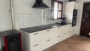 A kitchen with white cabinets, a black countertop, a stove, and a window with blinds. - Oasis of well-being, breathtaking sea view, pool, 4 bedrooms (Carraspite)