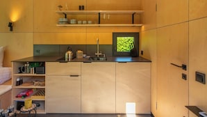Une cuisine compacte dotée de meubles en bois, d’un évier et d’une fenêtre donnant sur un paysage verdoyant.
