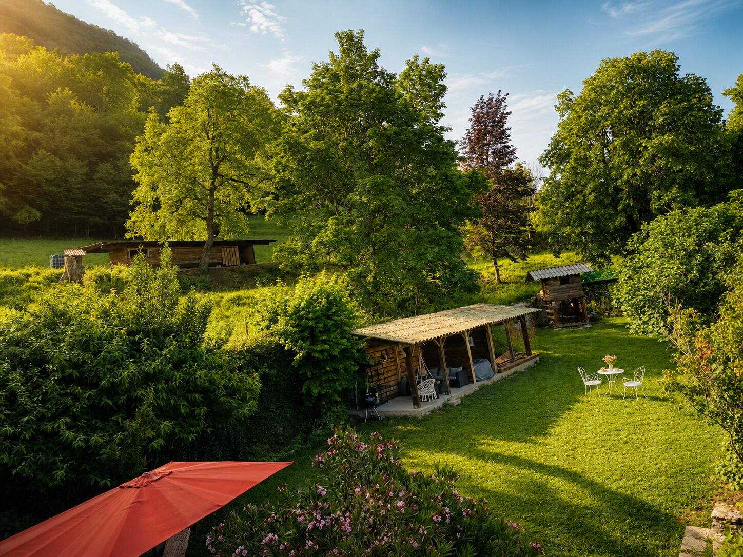 A rustic outdoor setting with a wooden cabin, a covered patio, and a red umbrella.