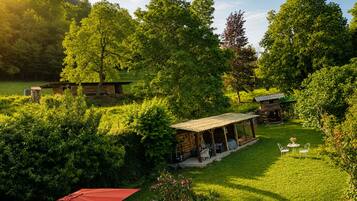 A rustic outdoor setting with a wooden cabin, a covered patio, and a red umbrella.