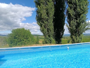 Una piscina con vistas despejadas del paisaje circundante, incluyendo árboles y colinas distantes.
