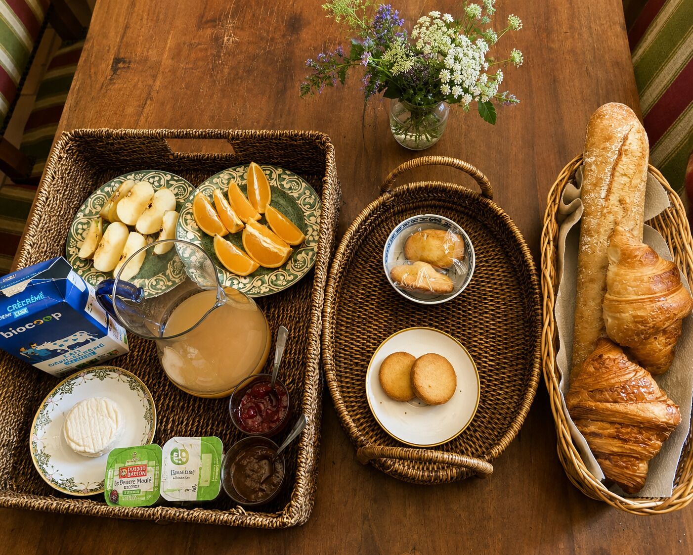 Uma mesa de madeira com uma variedade de pães, doces, frutas e laticínios para o café da manhã.