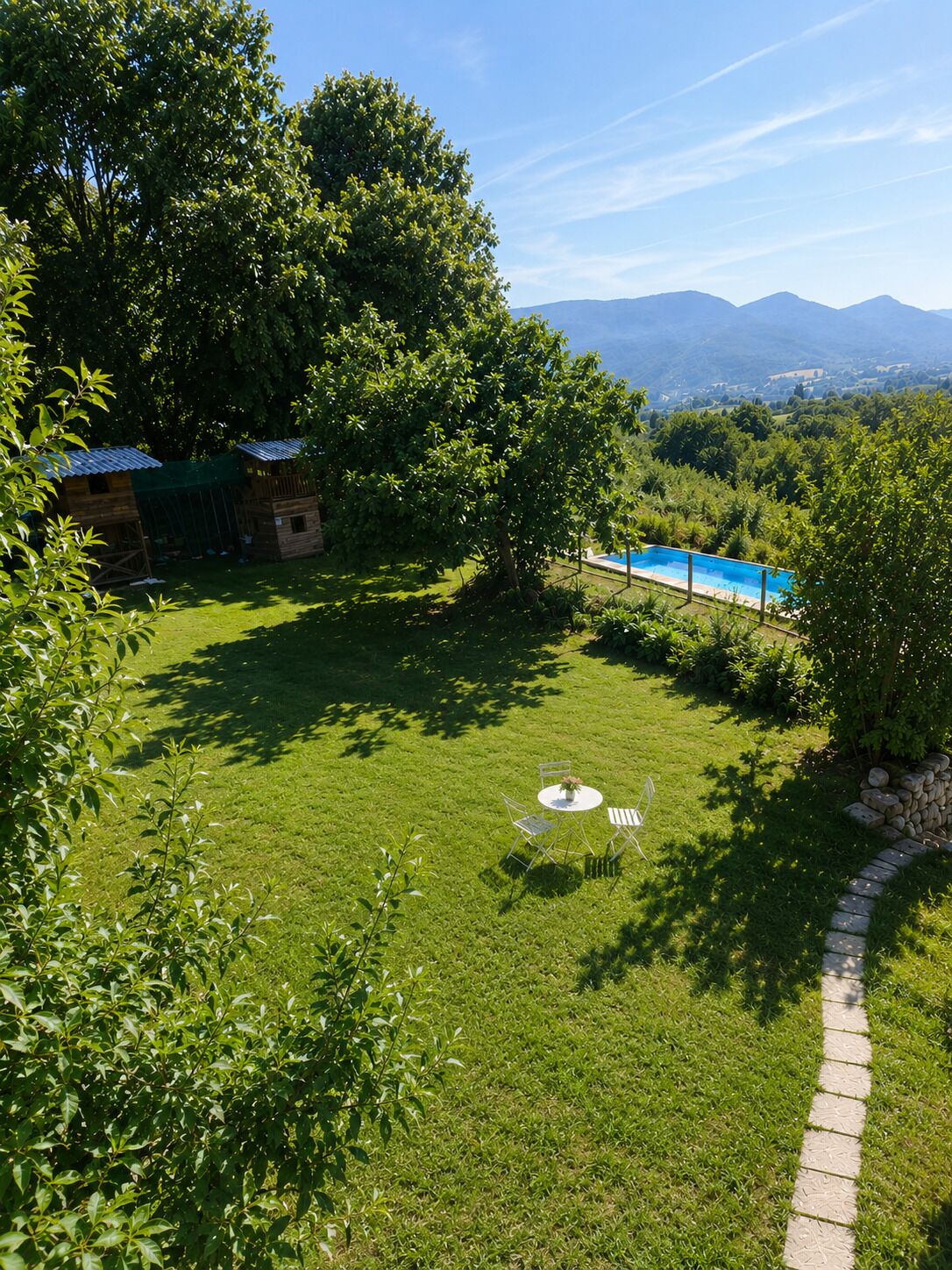 Un camp verd i abundant amb una piscina petita i una cabana de fusta.
