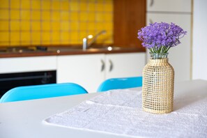 A kitchen with a yellow tiled backsplash, a sink, and a table with a woven vase of purple flowers. - Edo's Loft, Studio Apartment with Mezzanine (Alghero)