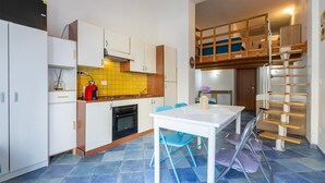 Una cocina compacta con comedor, un dormitorio en entrepiso y una escalera.