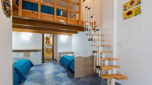 Una habitación con literas, una escalera de madera y una cama con colcha azul.