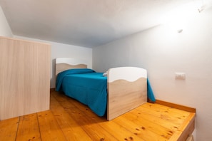 Ein Schlafzimmer mit Bett, Holzboden, weißen Wänden und einem Kleiderschrank.