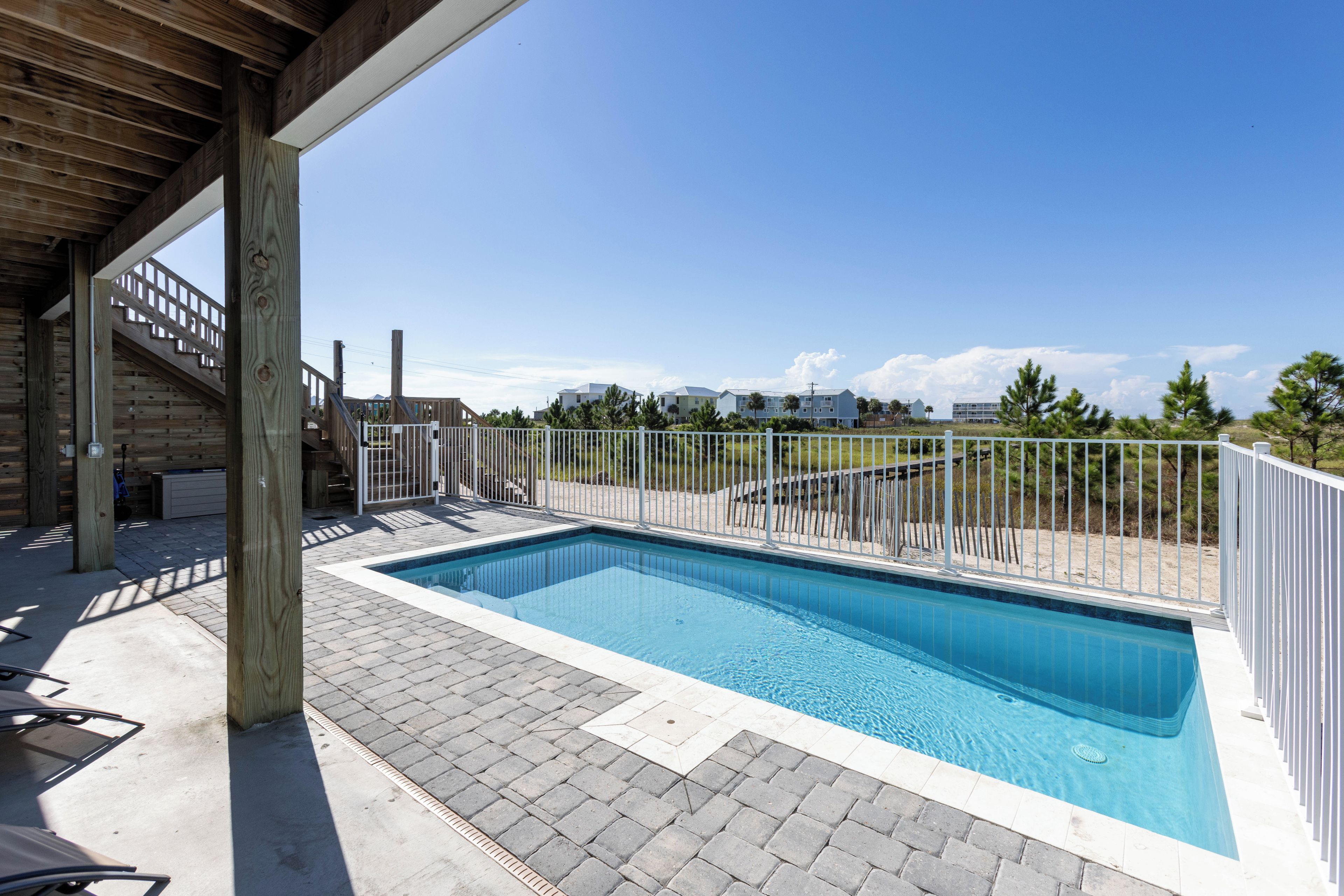 Piscina com deck de madeira e cerca branca.