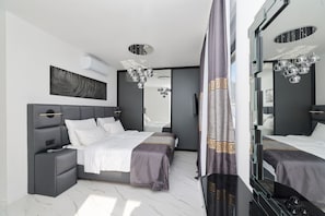 Ein modernes Schlafzimmer mit einem großen Bett, Nachttischen, einem Spiegel und einer Pendelleuchte.
