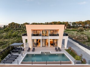 Um edifício moderno de dois andares com piscina e área de estar externa.