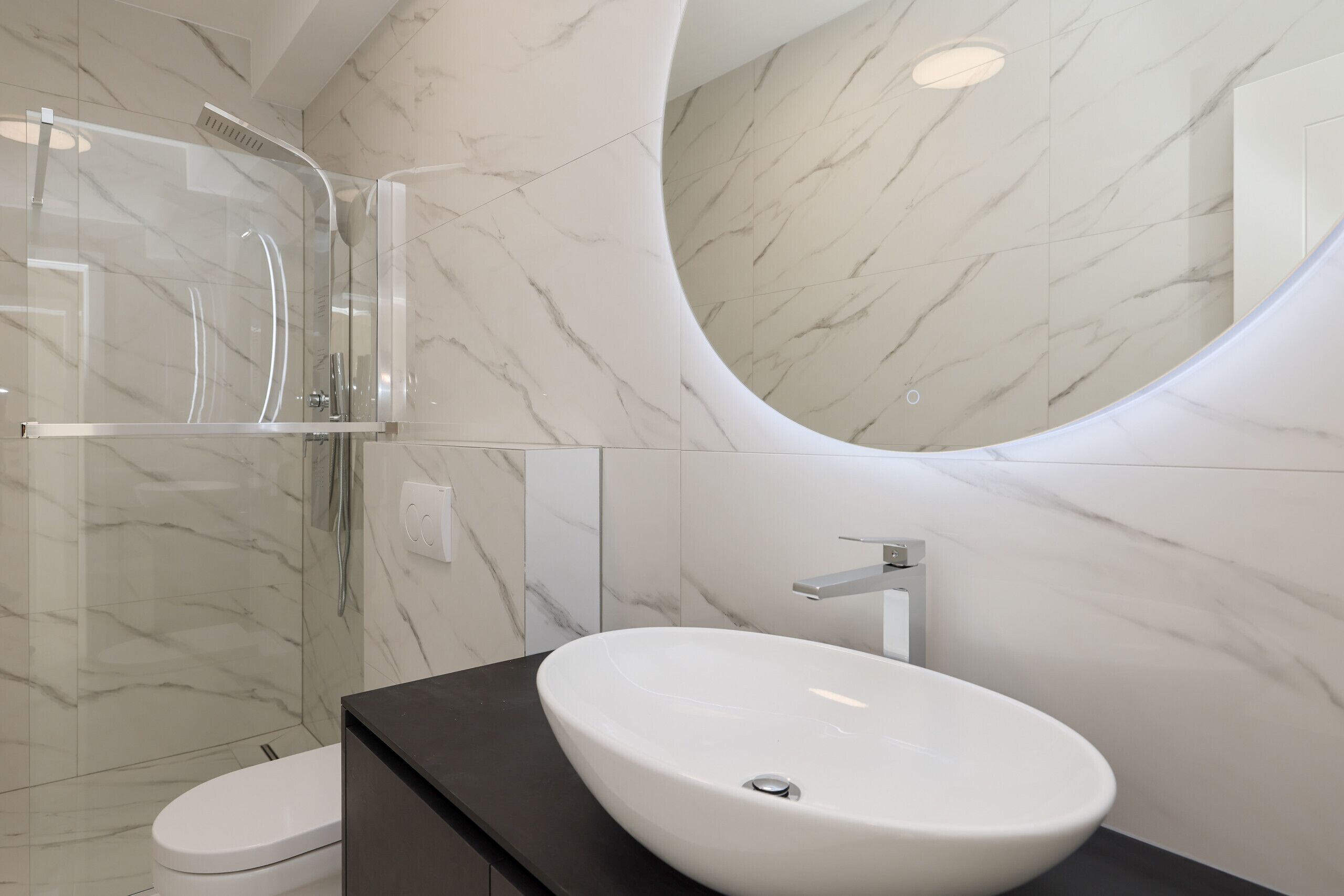 A bathroom with a white sink, a mirror, and a shower enclosure.