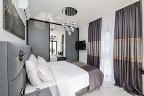 A modern bedroom with a large bed, a flat-screen TV, a ceiling light fixture, and a large mirror. - Villa Odeona ZadarVillas (Zadar)