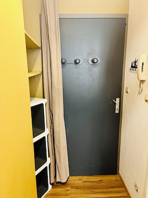 Ein schmaler Flur mit einer grauen Tür, einem Telefon und einer Steckdose.