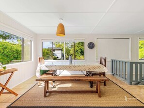 A dining area with a wooden table, chairs, a woven rug, and a hanging light fixture.