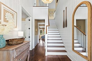 A staircase with wooden steps and white walls, a large mirror, and a decorative basket on a dresser. - NatureWalk "Sandy Paws" 3BR + Bunk | Sleeps 10 | Golf Cart | Pets OK | 🐶 (Santa Rosa Beach)