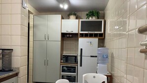 A compact kitchen with cabinets, a microwave, a refrigerator, and a water dispenser. - Apartamento Badalar do Sino - Belem - PA (Belém)