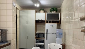 A compact kitchen with cabinets, a microwave, a refrigerator, and a water dispenser.