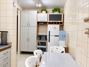 A compact kitchen with white cabinets, a built-in oven, a water dispenser, and a small dining area with a table and chairs.