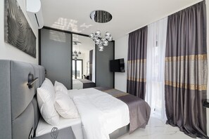 A modern bedroom with a large bed, a flat-screen TV, a ceiling light fixture, and a large mirror. - Villa Odeona Zadarvillas (Zadar)