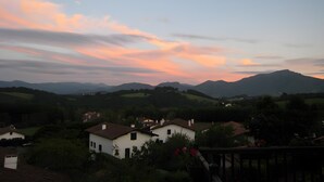 Un paysage rural avec des maisons, une montagne en arrière-plan et un ciel au coucher du soleil.