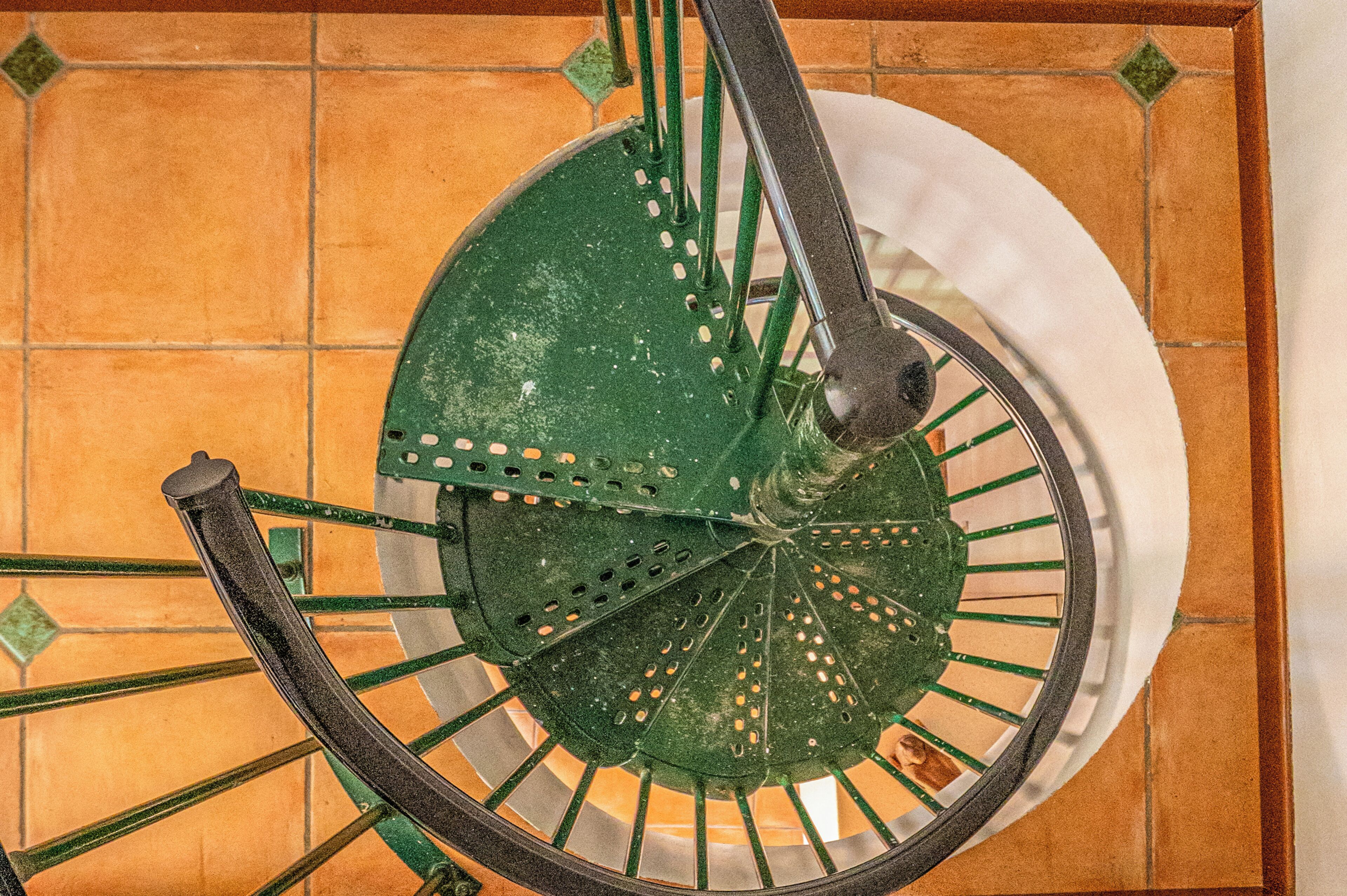 Eine Wendeltreppe mit grünen Geländern und einer weißen Wand.