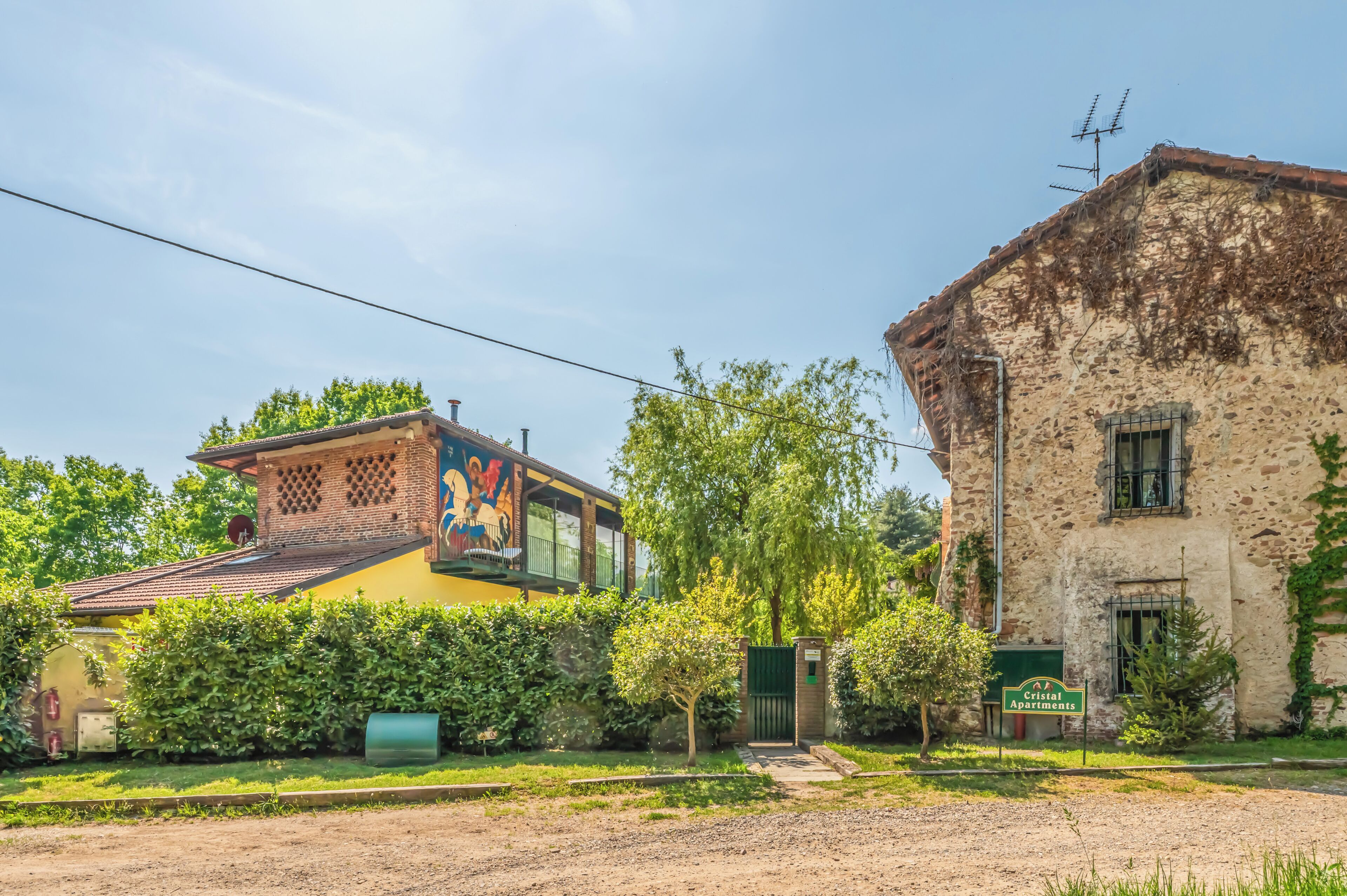 Un edificio con un mural, un letrero verde y una reja.