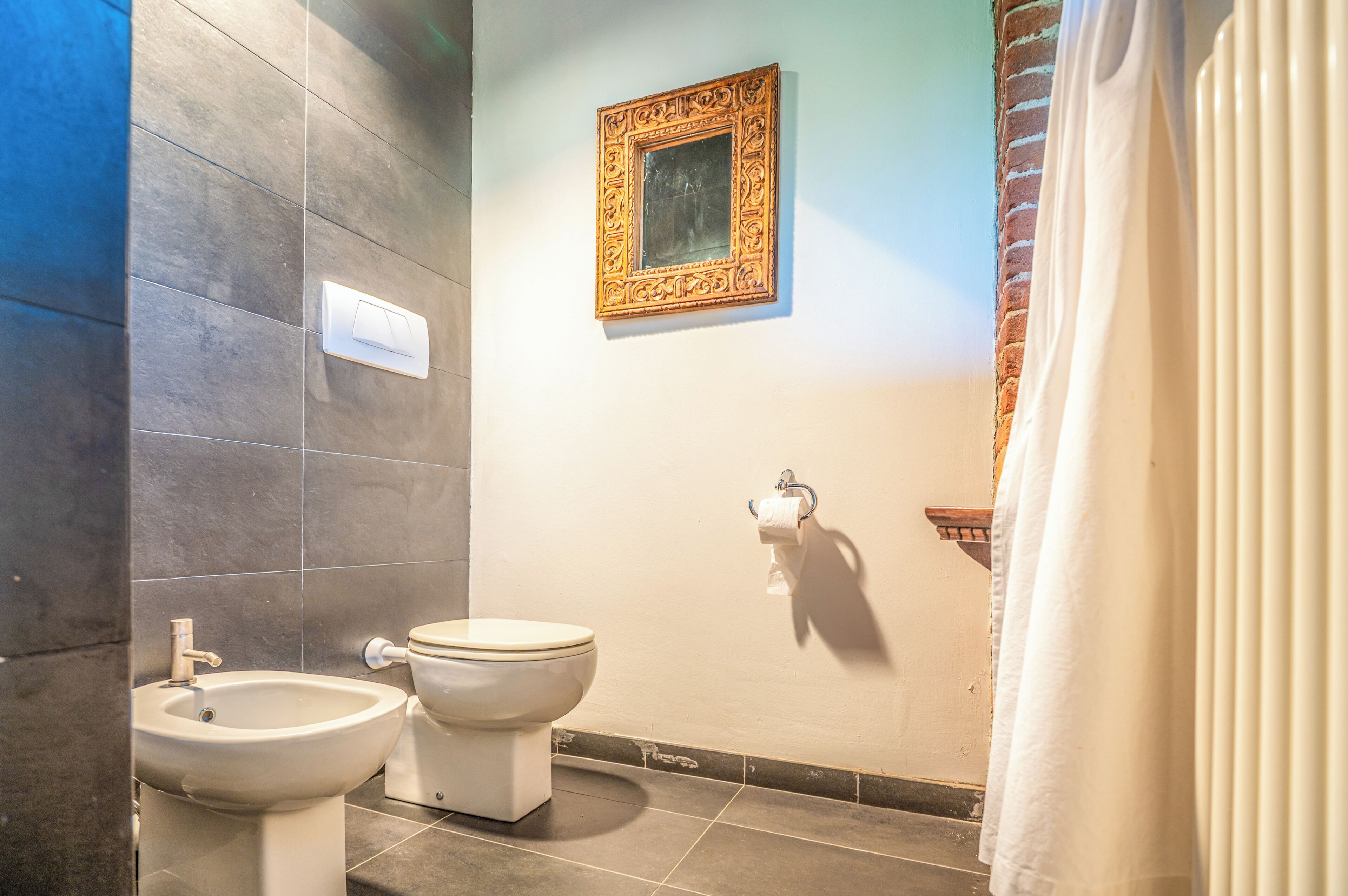 A bathroom with a bidet, toilet, and a framed picture on the wall.