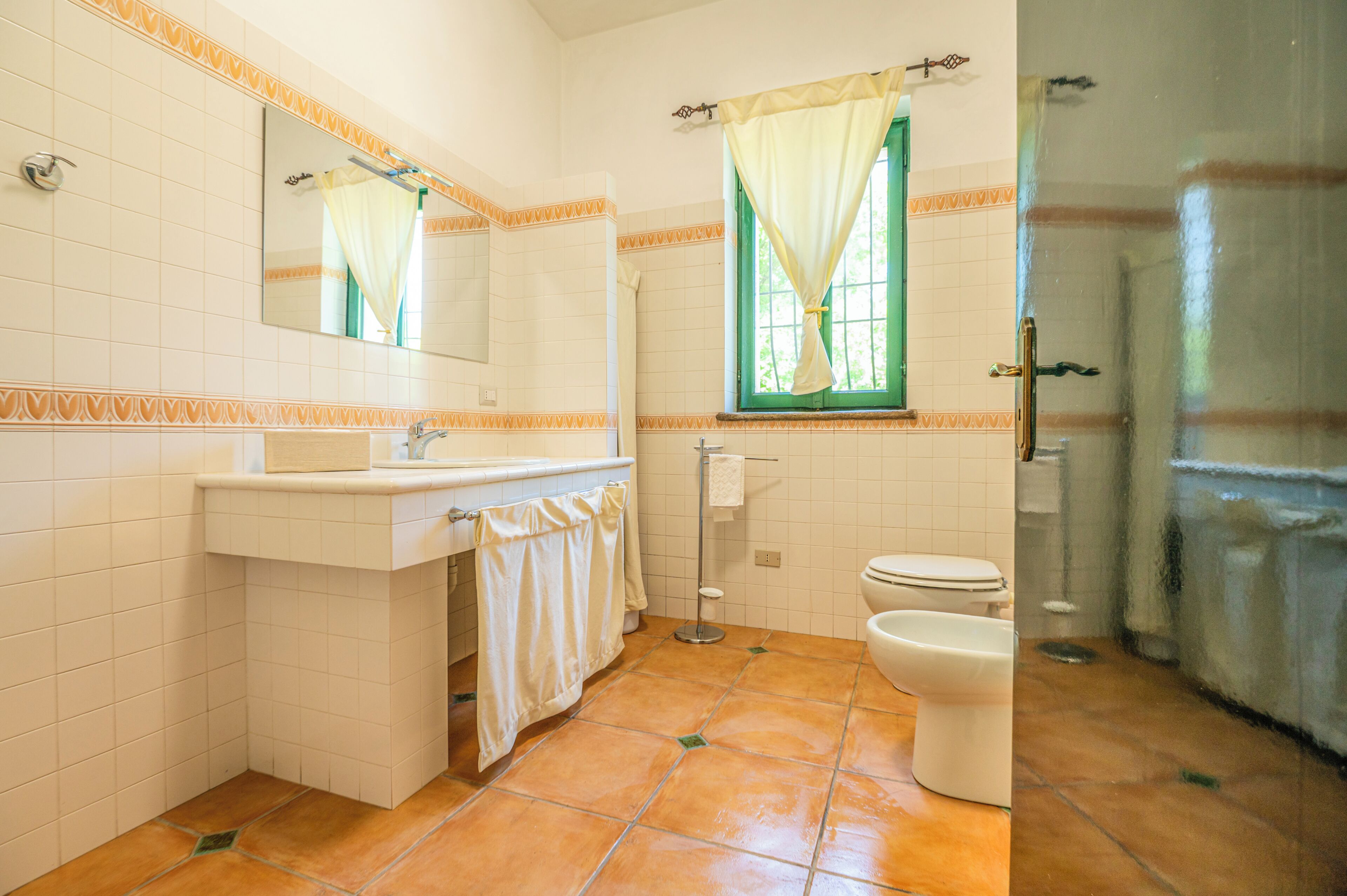 A bathroom with a sink, mirror, toilet, and shower area.