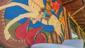 A room with a colorful mural, a bed, and a wooden ceiling structure.