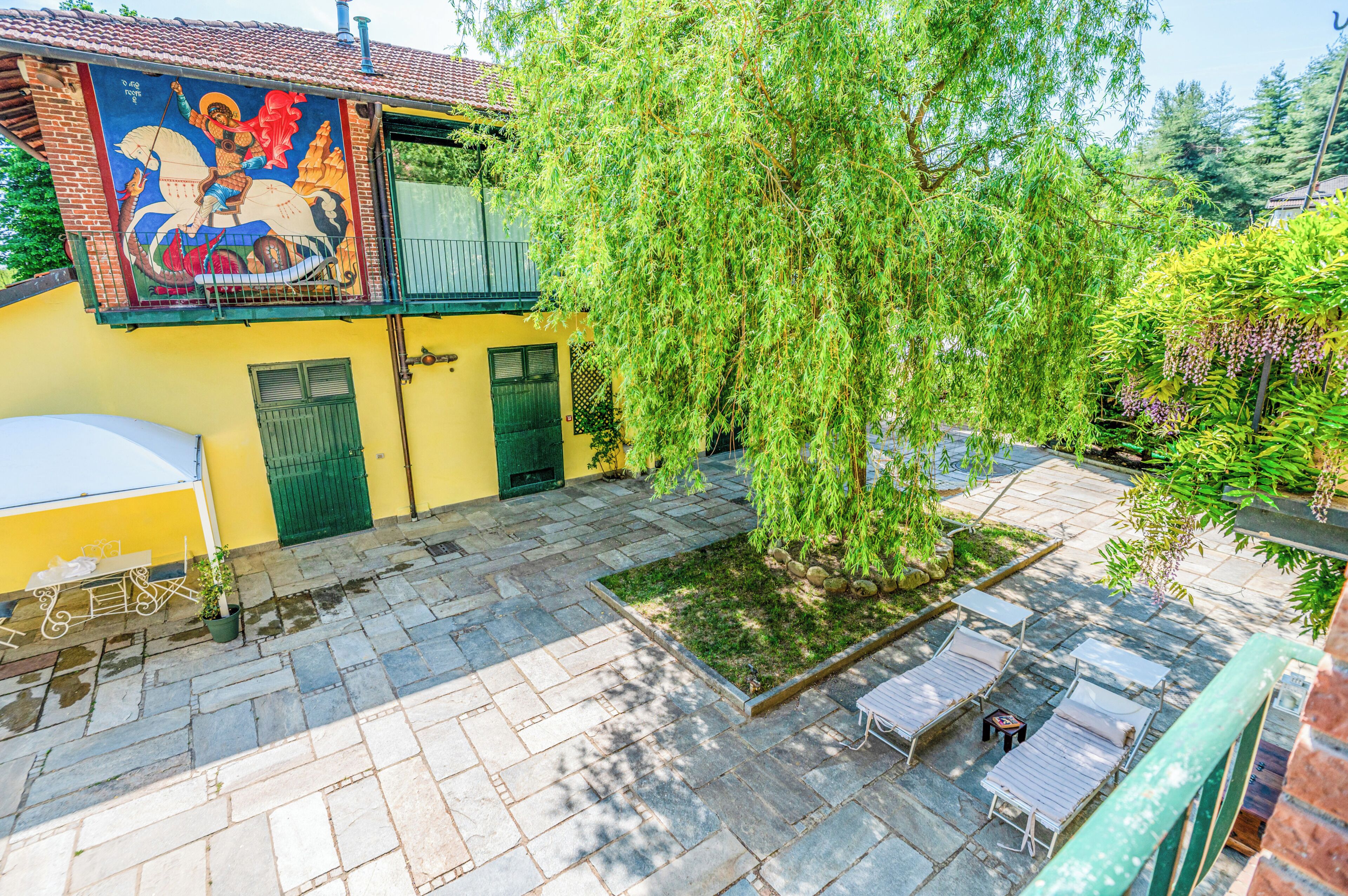 A courtyard with a mural, a tree, and outdoor seating.