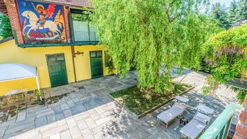 A courtyard with a mural, a tree, and outdoor seating.