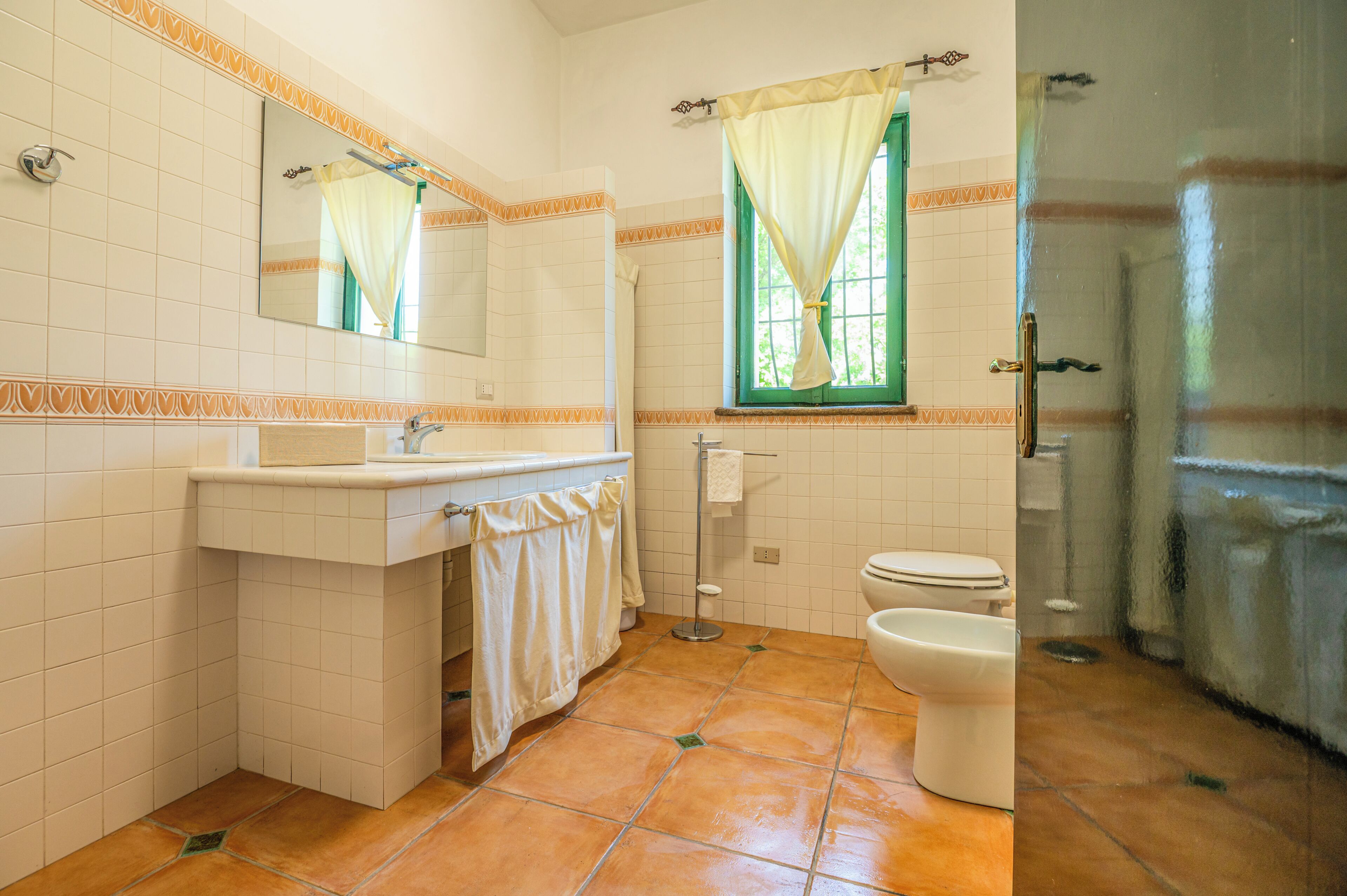 A bathroom with a sink, mirror, toilet, and shower.