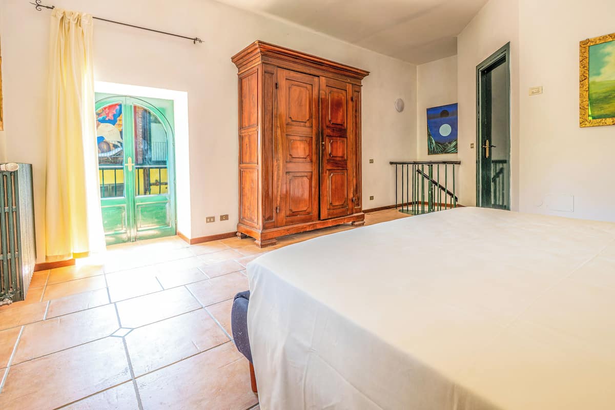 Une chambre à coucher avec un lit, une armoire, une porte et un tableau au mur.