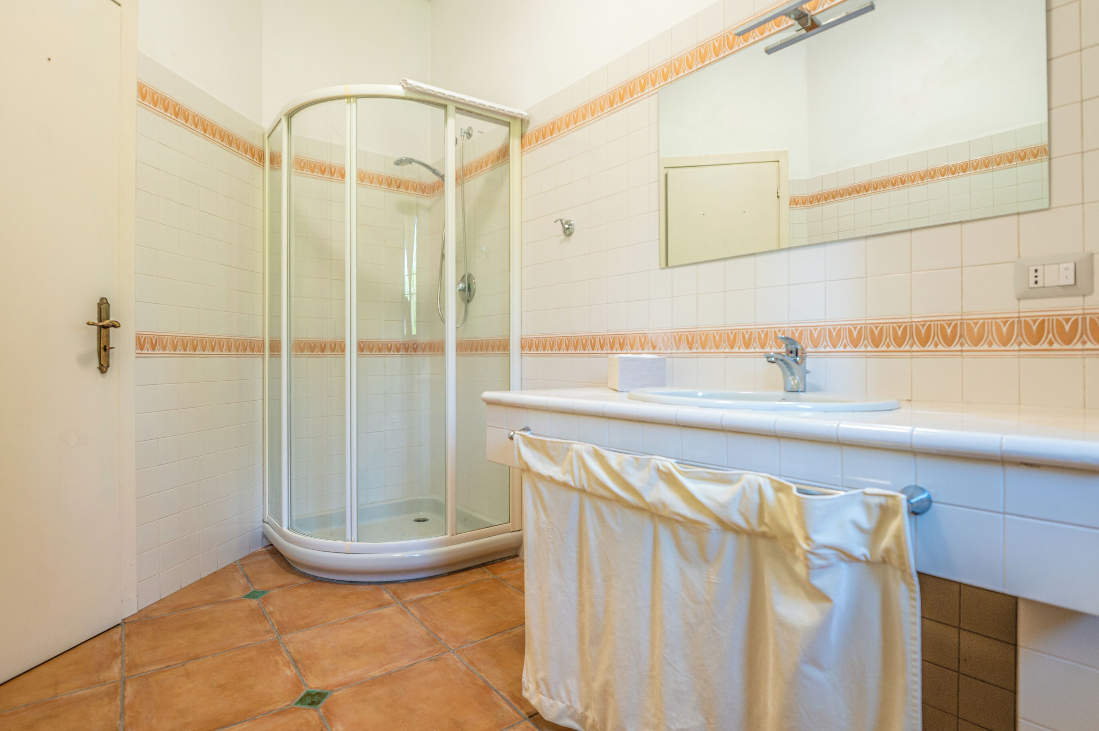 Un bagno con cabina doccia in vetro, un lavandino e un asciugamano appeso al muro.