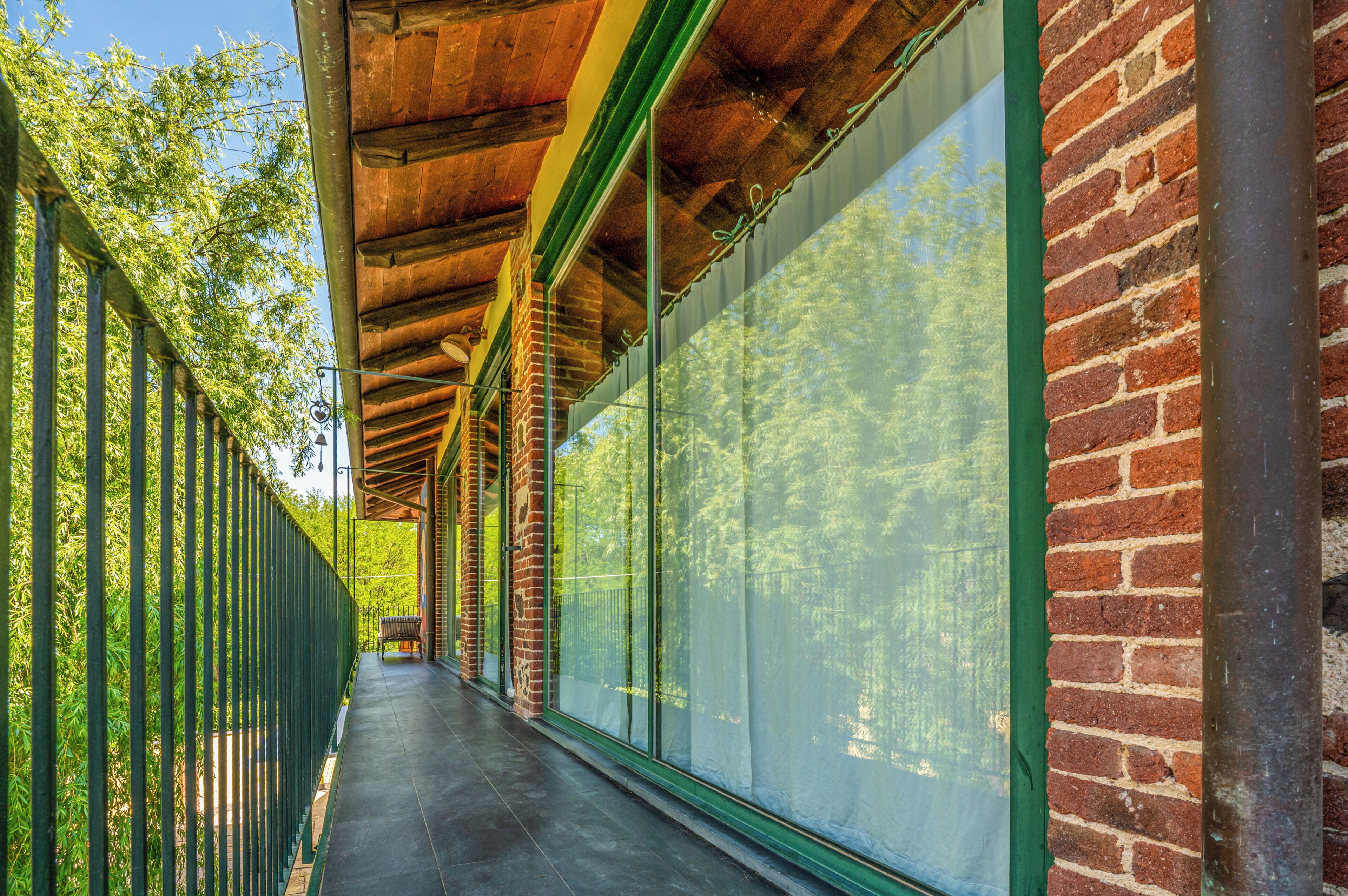 A covered corridor with a brick wall and large windows.