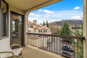 Ein Balkon mit Blick auf ein Wohngebiet, einen parkenden Wagen und einen Berg in der Ferne.