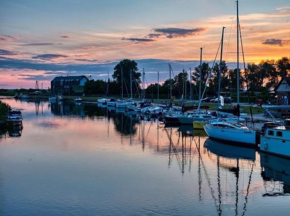 A marina with boats docked, calm water, and a building in the background.