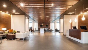 En rummelig lobby med receptionsdisk, siddeområde og moderne belysning.
