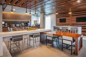 Una cocina moderna con una isla central, asientos tipo barra y una estación de café.