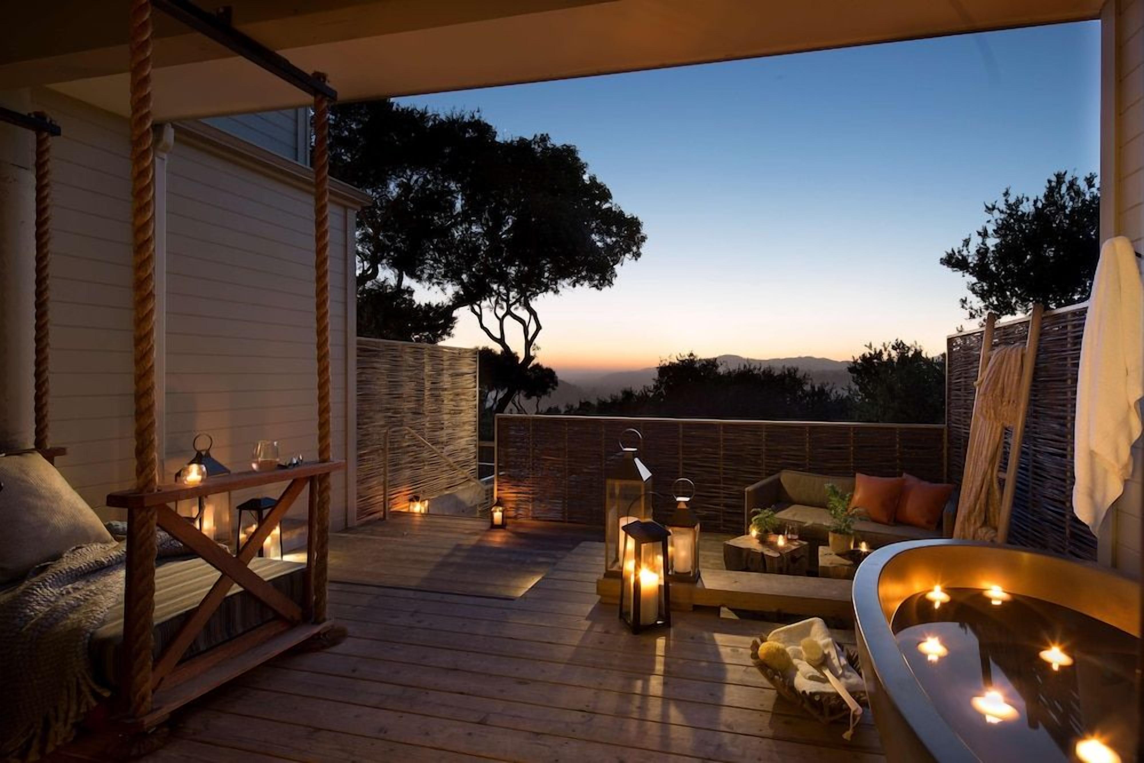 A wooden deck with seating, lanterns, and a view of the horizon.