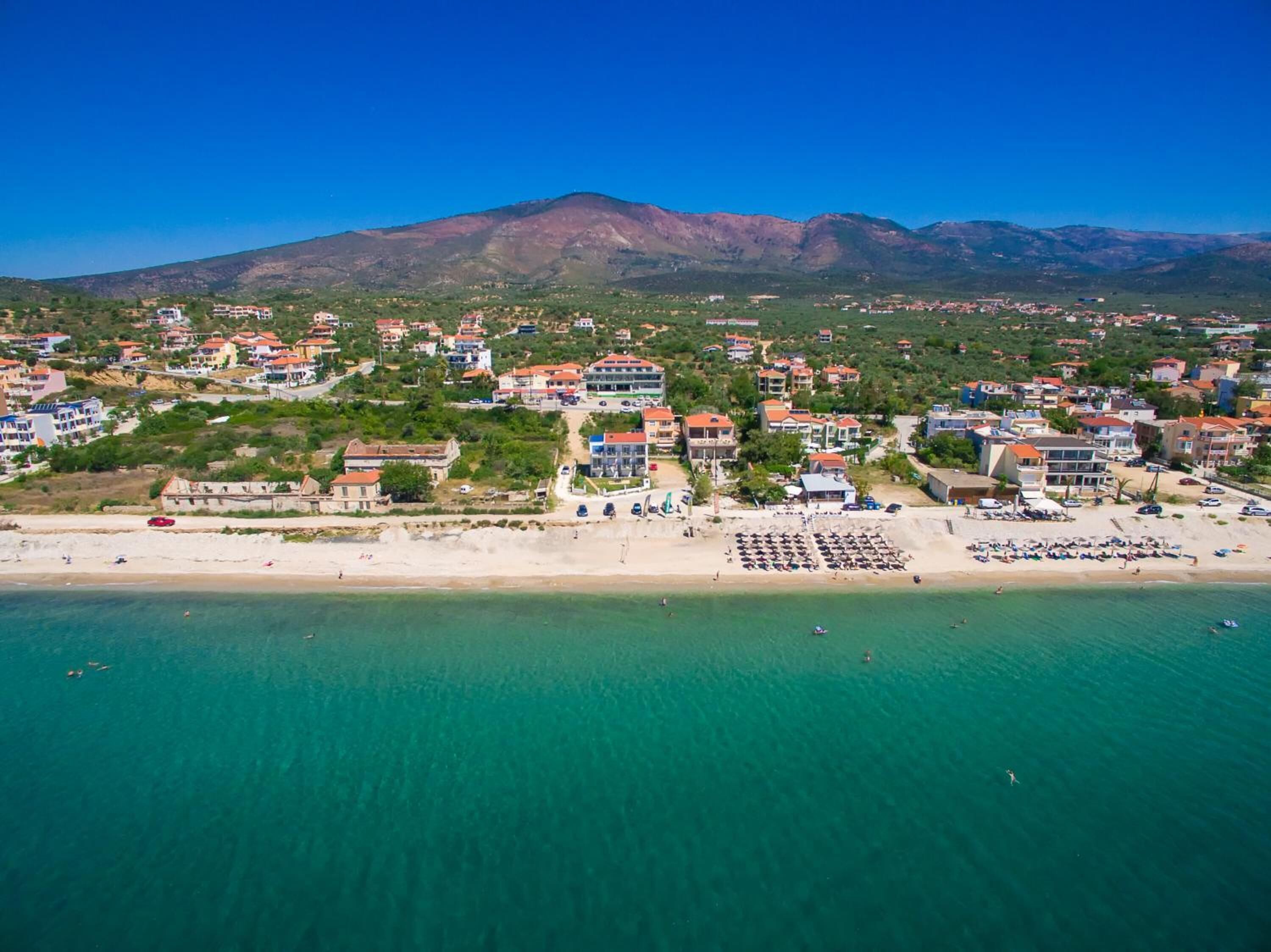 A coastal town with a beach, buildings, and a mountain in the background.