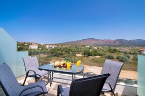 A balcony with a table set for two, overlooking a mountainous landscape with houses in the distance. - The Dome Luxury Hotel (Thasos)